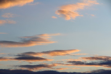 Fototapeta premium Clouds in the sky are illuminated from below by the red light of the sun. Sunset or sunrise scene at dusk.