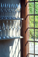 Fototapeta na wymiar Wine glasses on shelves near window