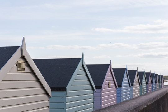 roofs of wooden huts of different pastel colors on the beach