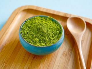 matcha tea on wooden salver on blue background with spoon. Concept healthy drink, detox, close up