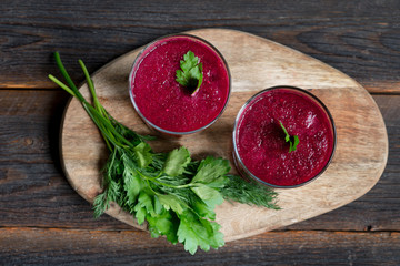 fresh beetroot smoothie glasses with greens on wooden background, top view