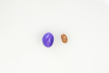A larger jelly bean bullies a small, different bean. 
