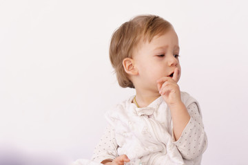 A little boy of 2 years in a sleeping bag shows a gesture quietly holding a finger to his lips on the bed. A handsome boy in pajamas is sitting on the bed and smiling. Concept of sweet dreams, family