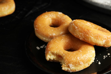Sweet delicious glazed donuts on black table