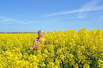 Mature woman stands in flowering rapeseed field