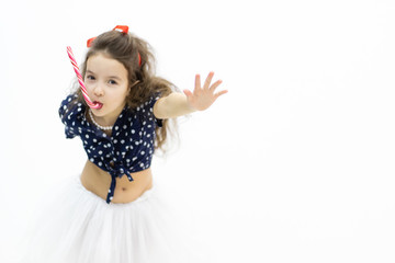 Girl looking at a camera with a candy in her mouth keeping her hand in front of herself.