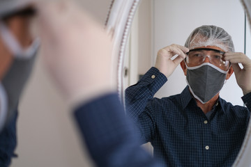 Caucasian man wears protective medical mask, bonnet and glasses