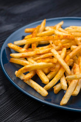 french fries on a blue plate and black background