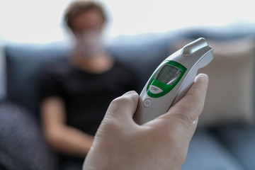 The father is checking temperature his son's with infrared thermometer at the home