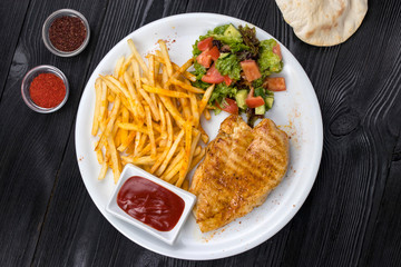 chicken, french fries, sauce on a white plate