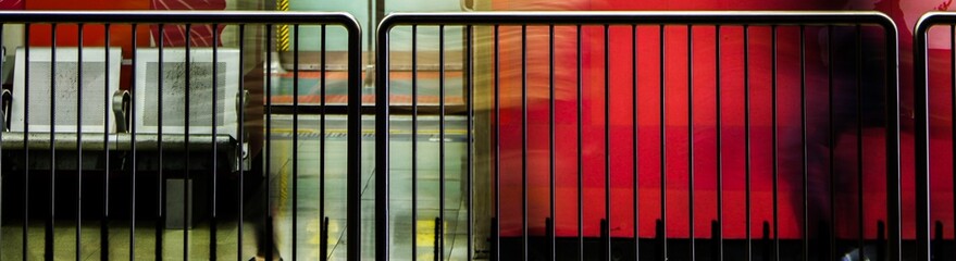 Metal barricades and empty chairs in subway station with red wall