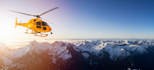 Yellow Helicopter flying over the Rocky Mountains during a sunny sunset. Aerial Landscape from British Columbia, Canada near Vancouver. Composite. Canadian Panoramic Nature Background