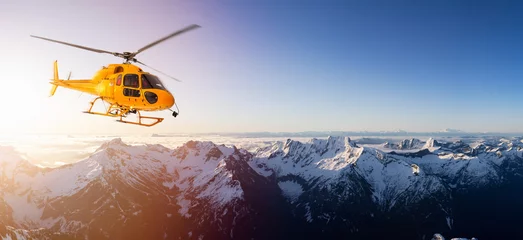 Abwaschbare Fototapete Hubschrauber Yellow Helicopter flying over the Rocky Mountains during a sunny sunset. Aerial Landscape from British Columbia, Canada near Vancouver. Composite. Canadian Panoramic Nature Background