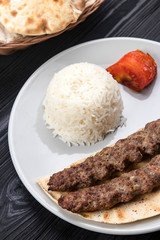meat on pita bread with rise on a black wooden background