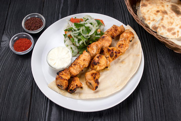 grilled meat on pita bread with salad on a black wooden background