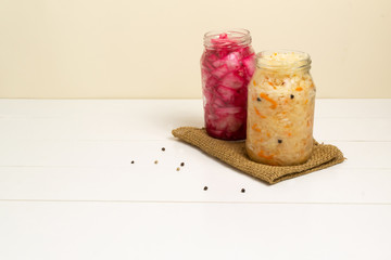 Fermented vegetables with spices in glass jars on burlap on a white background. Copy space.