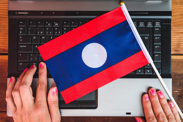 woman hands and flag of Laos on computer, laptop keyboard