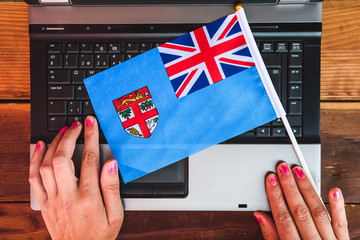 woman hands and  flag of Fiji on computer, laptop keyboard
