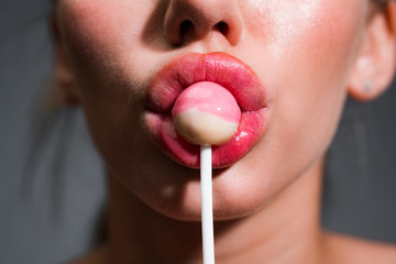 Woman lips sucking lollypop. Woman holding lollipop in mouth, close up. Red lips, sensual and sexy...