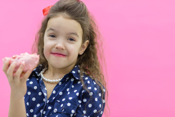 Funny smiling little girl with colorful donut on empty background.