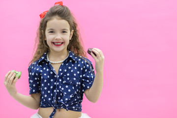 A girl holding two macaroons in hands.
