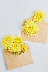 wedding concept. beautiful composition of yellow flowers and a envelope kraft on a white desk. flat lay, top view