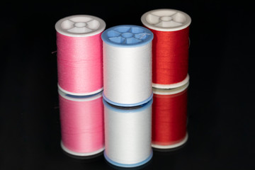 Spools of colorful cotton thread on a mirror for reflection