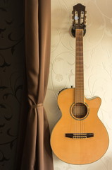 Obraz na płótnie Canvas acoustic guitar on a wall holder - good warm color match, cozy interior.