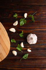 Obraz na płótnie Canvas .Juicy, ripe, fragrant garlic with leaves of green fresh parsley lie on a dark wooden table.