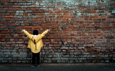 A girl poses against a brick wall. Young model.