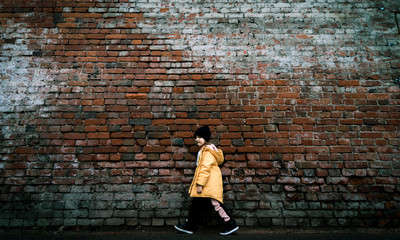 A girl poses against a brick wall. Young model.