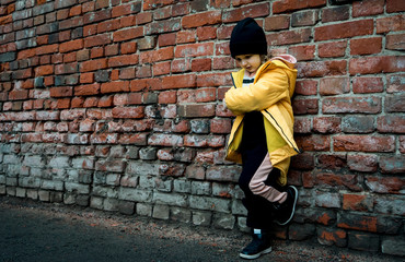 A girl poses against a brick wall. Young model.