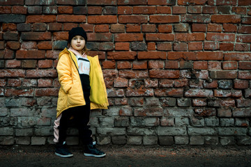 A girl poses against a brick wall. Young model.