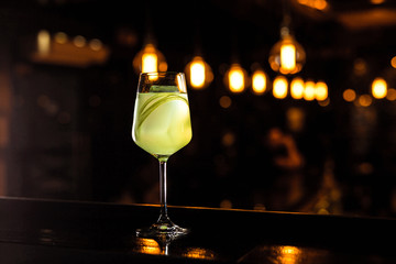 A beautiful light green cocktail with celery in a wine glass, bokeh lights, selective focus, horizontal