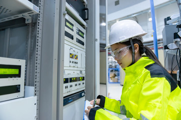 Electrical engineer woman checking voltage at the Power Distribution Cabinet in the control room,preventive maintenance Yearly,Thailand Electrician working at company