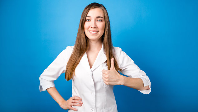 Portrait of a girl doctor in a white medical coat on a blue background showing a class