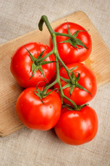 Juicy red tomatoes on a cutting board with a knife. Top view.