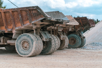 Three large mine trucks are parked by the hill of the mineral ready for transport