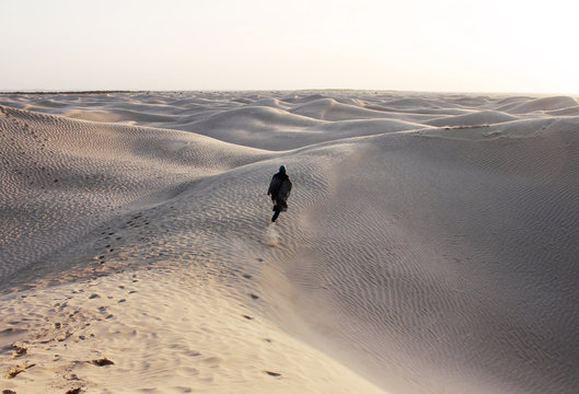 PERSON RUNNING A DESERT DUNE AT SUNSET