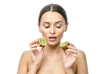 close-up portrait of a girl with clear skin holding a kiwi fruit to her face on a white background