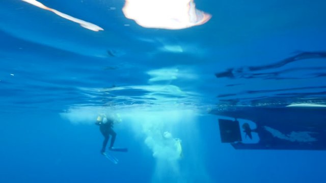 underwater scenery of scuba divers with boat end or begining of dive 