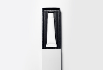 Close-up of cosmetic tube with mock-up, packaging in black box on white background.