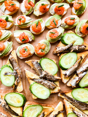 Tartlets, sandwiches with red caviar, salmon, sprats, avocado and cucumber close up. Tasty appetizer for guests. Gourmet food. Texture of caviar. Top view. Vertical. Seafood.