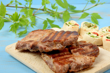 grilled meat on a kitchen board with pieces of colorful tortilla
