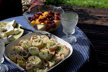 an empty glass, rolled up tortilla, fruit, cheese and wine on the terrace table
