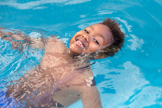 Little african child splashing out in the pool