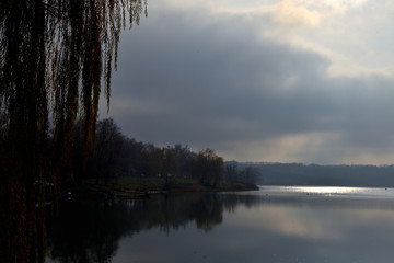 Obraz premium Landscape by the river. Mirror on the water. Water reflection. Boat near the water. The boatman in the fog. The rays of the sun on the water. Ukraine