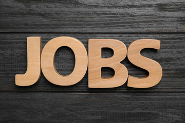 Fototapeta premium Word JOBS on wooden background, flat lay. Career concept