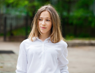 Portrait of a young blonde girl in white shirt and blue jeans