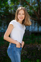 Fototapeta premium Portrait of a young blonde girl in white t-shirt and blue jeans